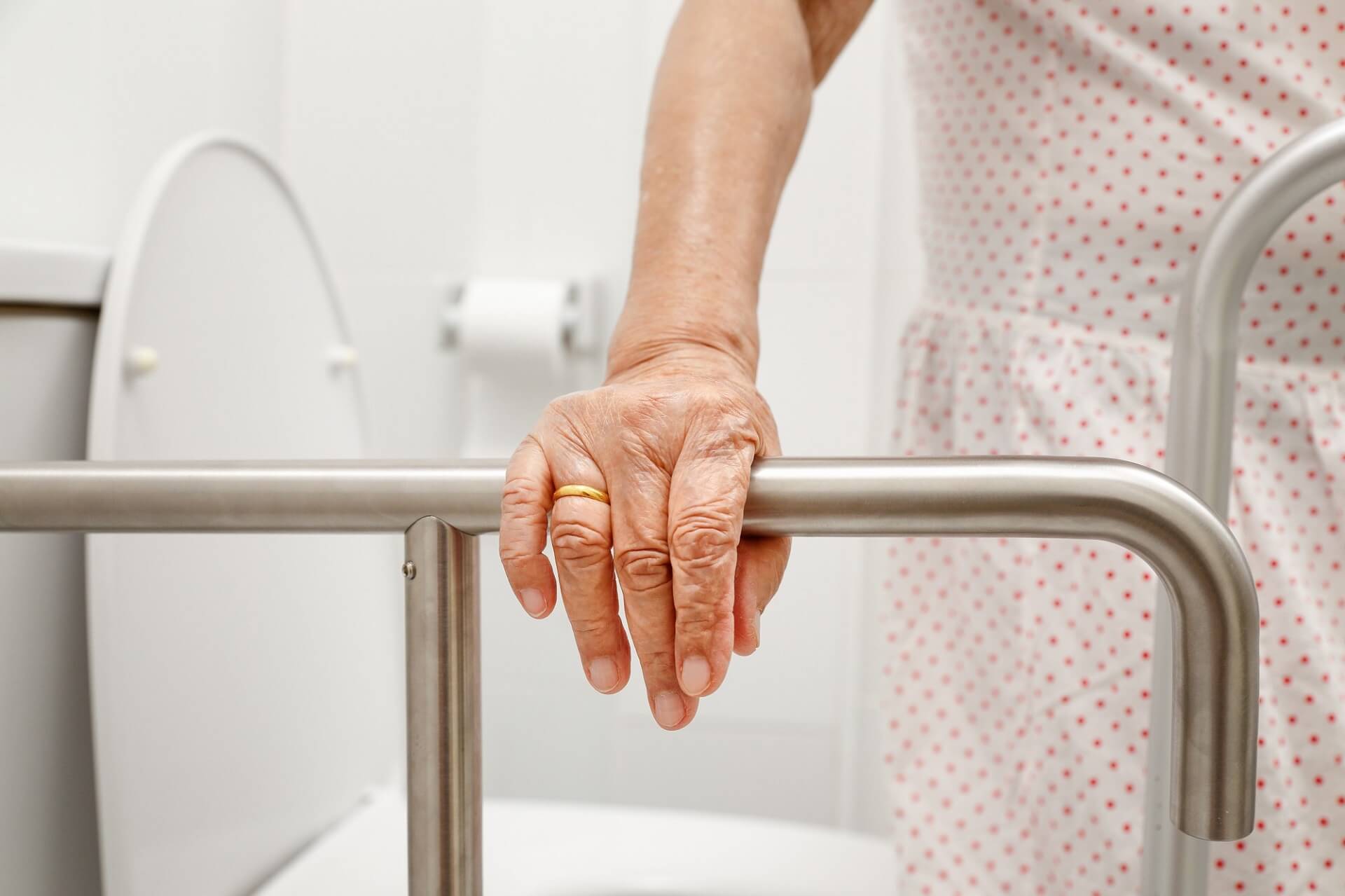 A senior woman using a grab bar in the bathroom for support to prevent falls.